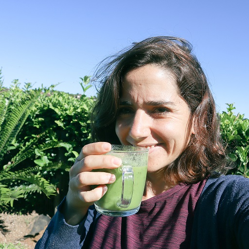 ענת סרי אישה עצמאית שותה שייק ירוק על רקע עלים ירוקים
