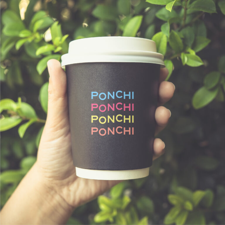 יד מחזיקה כוס לשתייה חמה ועליה מודפס 4 פעמים בצבעים שונים המילה PONCHI